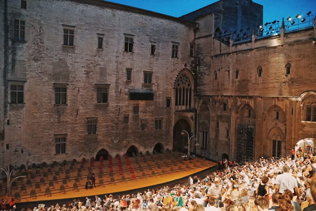 A Festival d’Avignon theater performance in the courtyard of the Palais des Papes [Photo credit: Tao Qi/Unsplash]