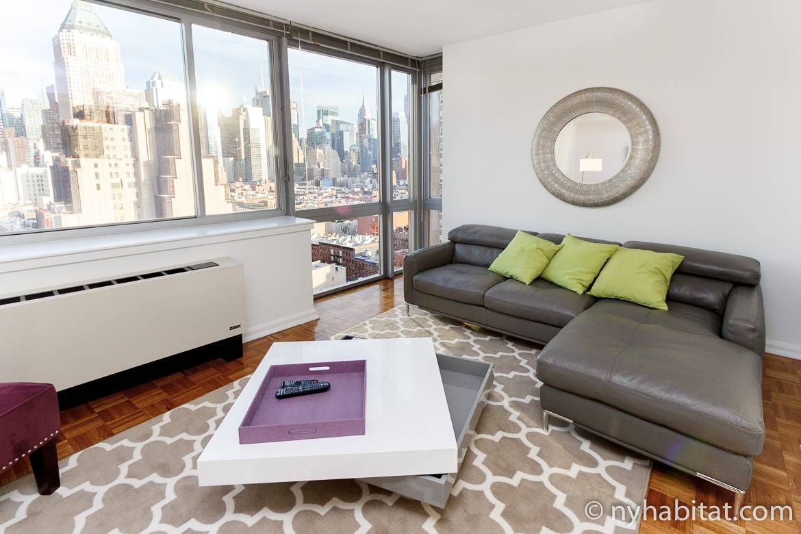 Bild von Wohnbereich in NY-16172 mit Sofa, Kaffeetisch und großen Fenstern.