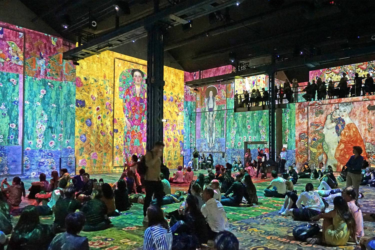 Foto von Leuten, die sich die digitale Ausstellung von Klimt im Atélier des Lumières ansehen.