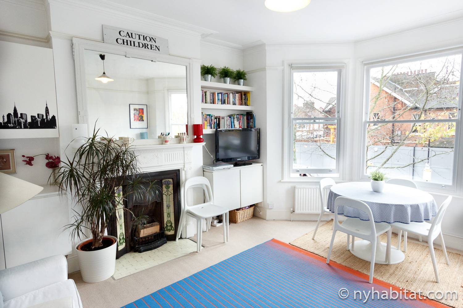 Foto des Wohnzimmers der Wohnung LN-486 mit Esstisch und Stühlen, Kamin und Bücherregal.