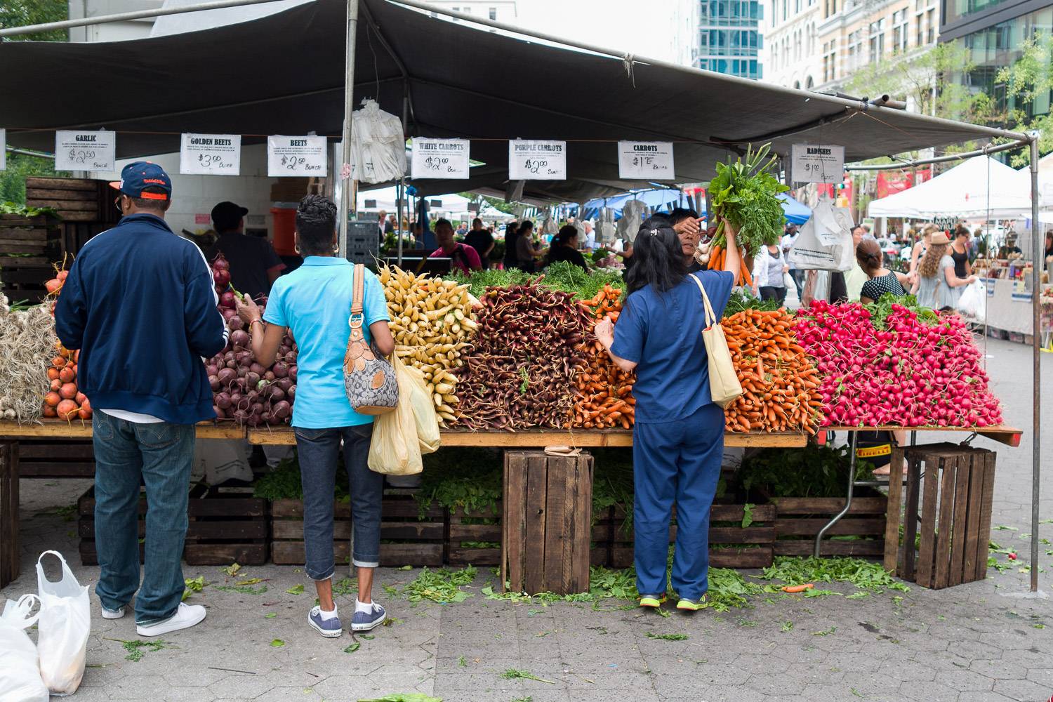 Bild des Union Square Greenmarkets mit Kunden, die aus dem aufgestellten Obst und Gemüse auswählen .