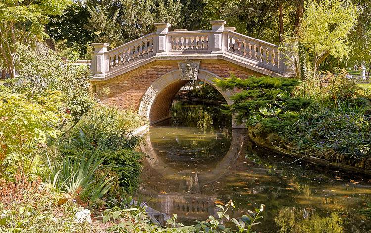 Abbildung einer kleinen gewölbten Brücke über dem Wasser im Parc Monceau. Foto: BikerNormand [CC BY-SA (https://creativecommons.org/licenses/by-sa/2.0)] 