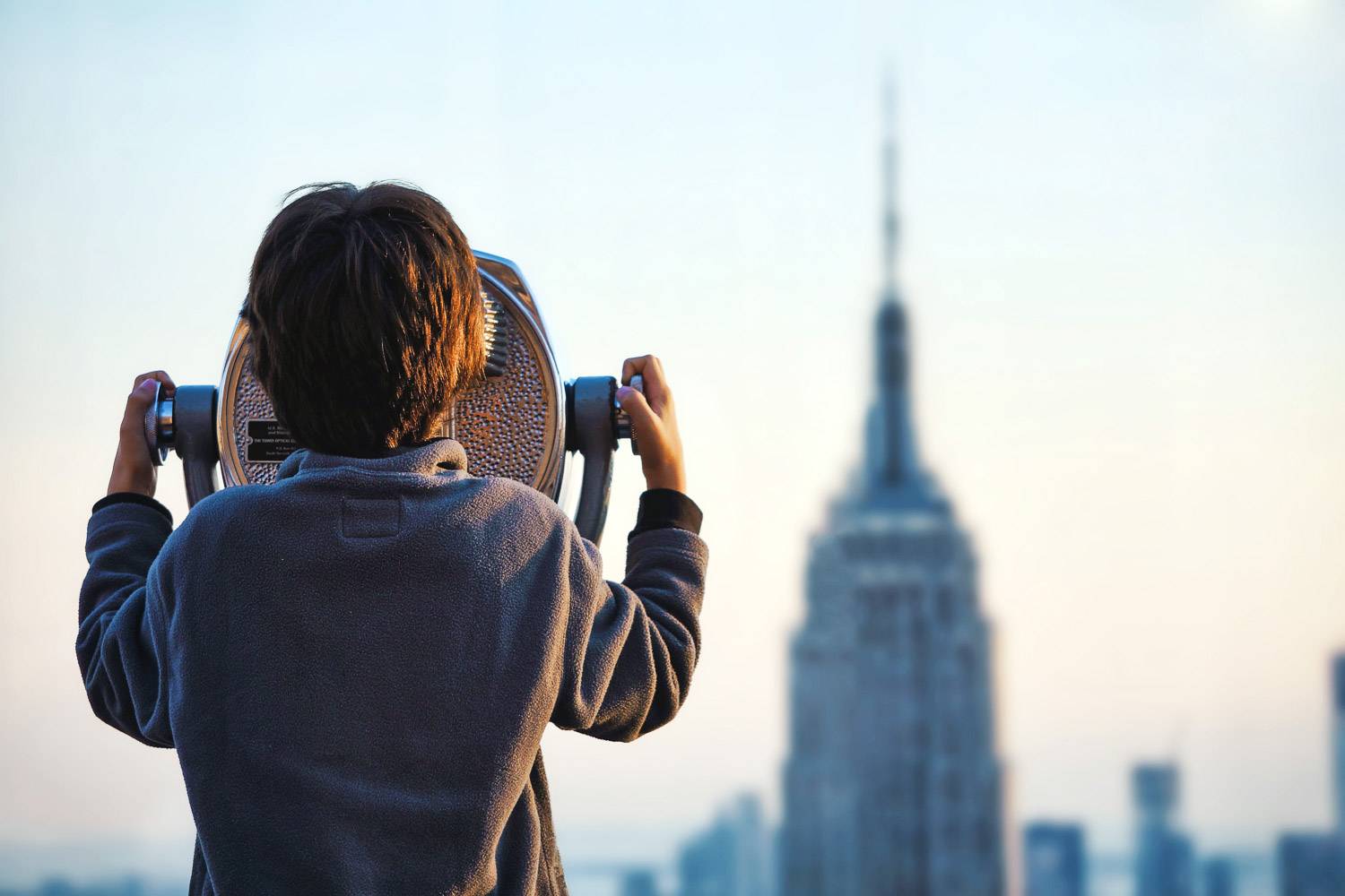 Bild von einem Kind, das durch ein Teleskop auf das Empire State Building schaut (Bild: Unsplash)