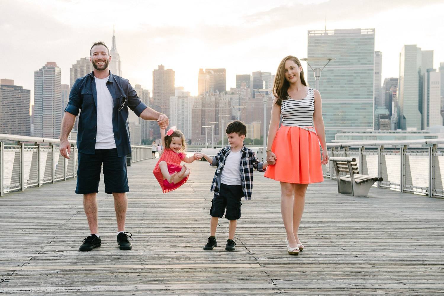 Bild einer Familie, die mit ihren Kindern spazieren geht, während die Skyline von New York im Hintergrund zu sehen ist (Bild: Kimberly for Flytographer in NYC)
