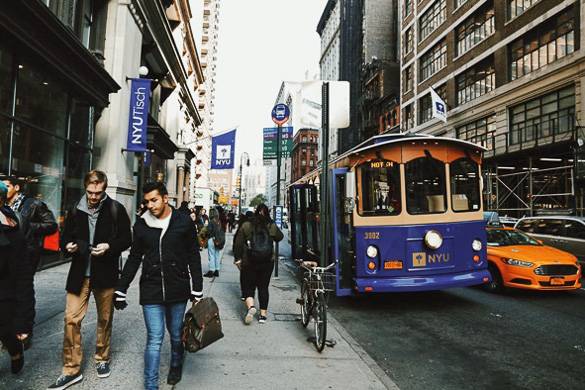 Bild der NYU Tisch und einer Straße mit Studenten und einem NYU Bus