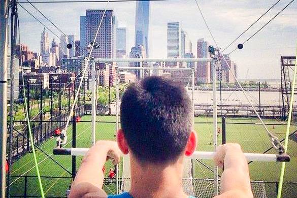 Bild eines Mannes, der das Trapez hält und zum Freedom Tower im Hintergrund blickt