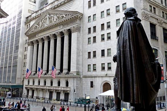 Bild der NYSE in der Wall Street mit der amerikanischen Flagge und der Statue im Vordergrund.