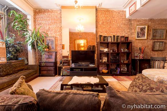 Bild des Wohnzimmers in NY-15886 mit freiliegenden Backsteinwänden und Kronleuchter über den Sofas.