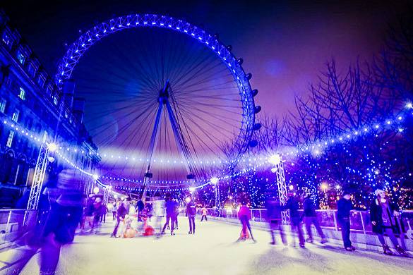 Bild von Menschen beim nächtlichen Schlittschuhfahren mit dem beleuchteten London Eye im Hintergrund