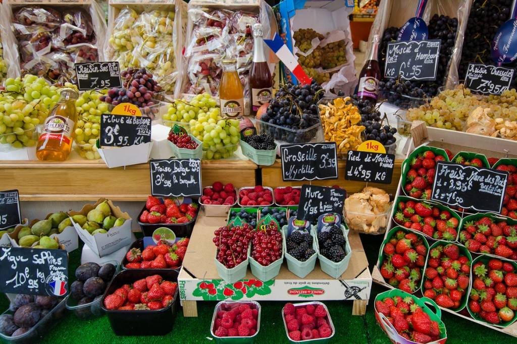 Photo d'une table couverte de fruits rouges, de raisins et d'autres fruits dans un marché français