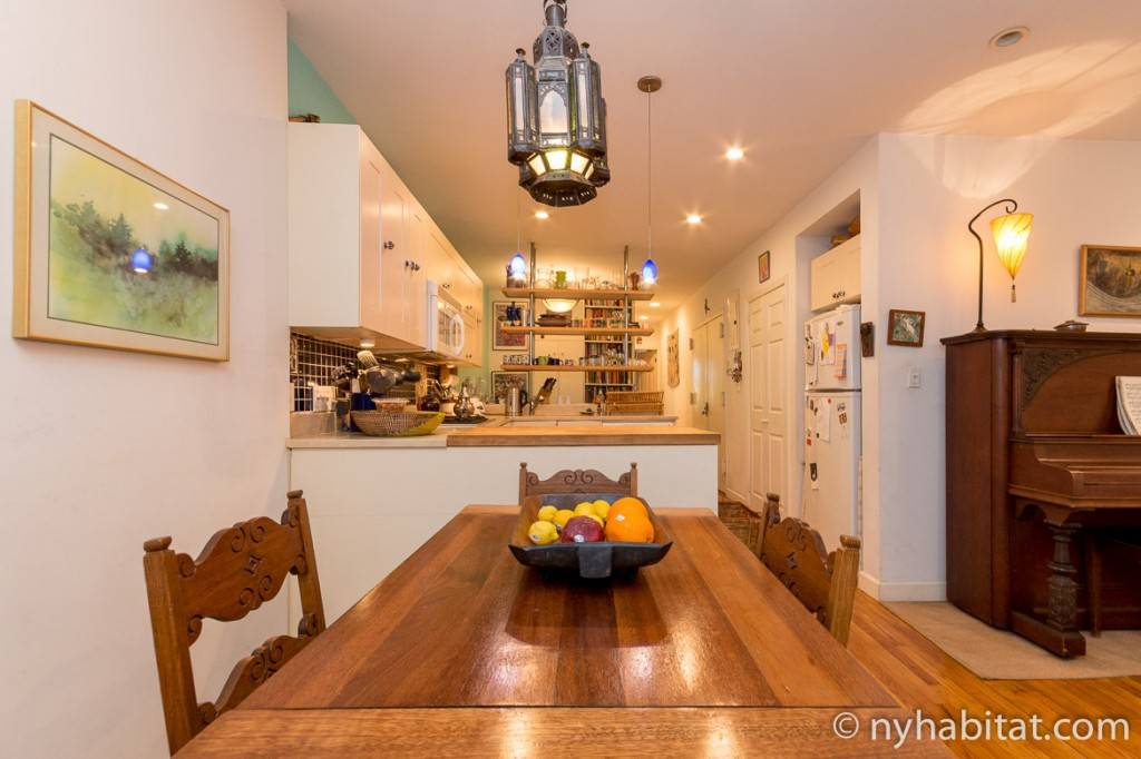 Photo d’un appartement avec une table en bois et une cuisine de couleur blanche.