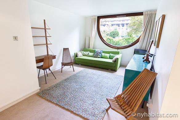 Photo du salon de l’appartement LN-1037 et de sa fenêtre en forme de hublot avec vue sur les arbres