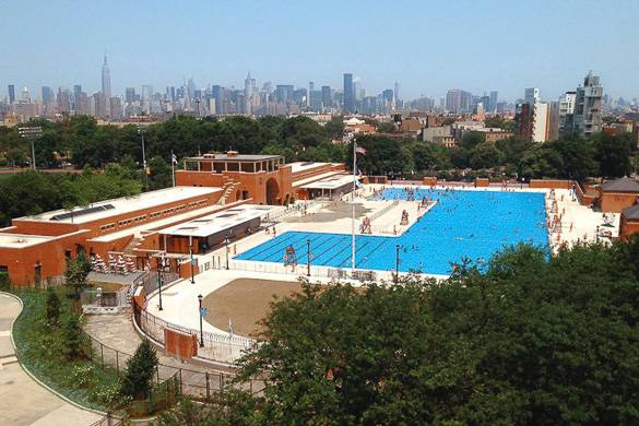 Photographie de la piscine publique de McCarren Park avec la skyline de Manhattan au loin