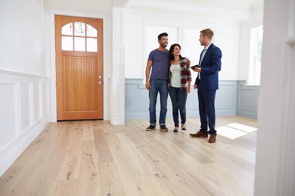 Photo d’un agent immobilier en conversation avec des clients à l’intérieur d’un logement