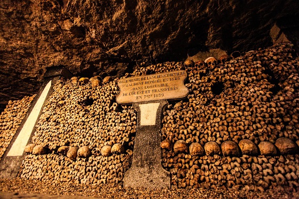 Photo de crânes et d’os disposés de manière artistique dans les Catacombes de Paris