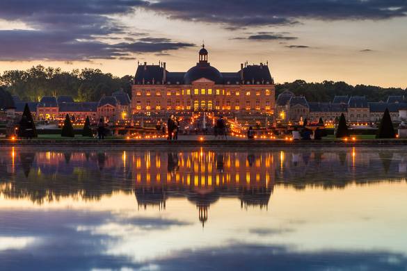 Photo d’un grand château au bord d’un lac au coucher du soleil