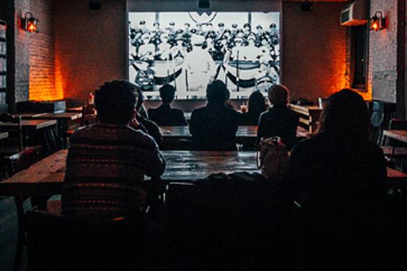 Photo de personnes attablées qui visionnent un film au Videology Bar