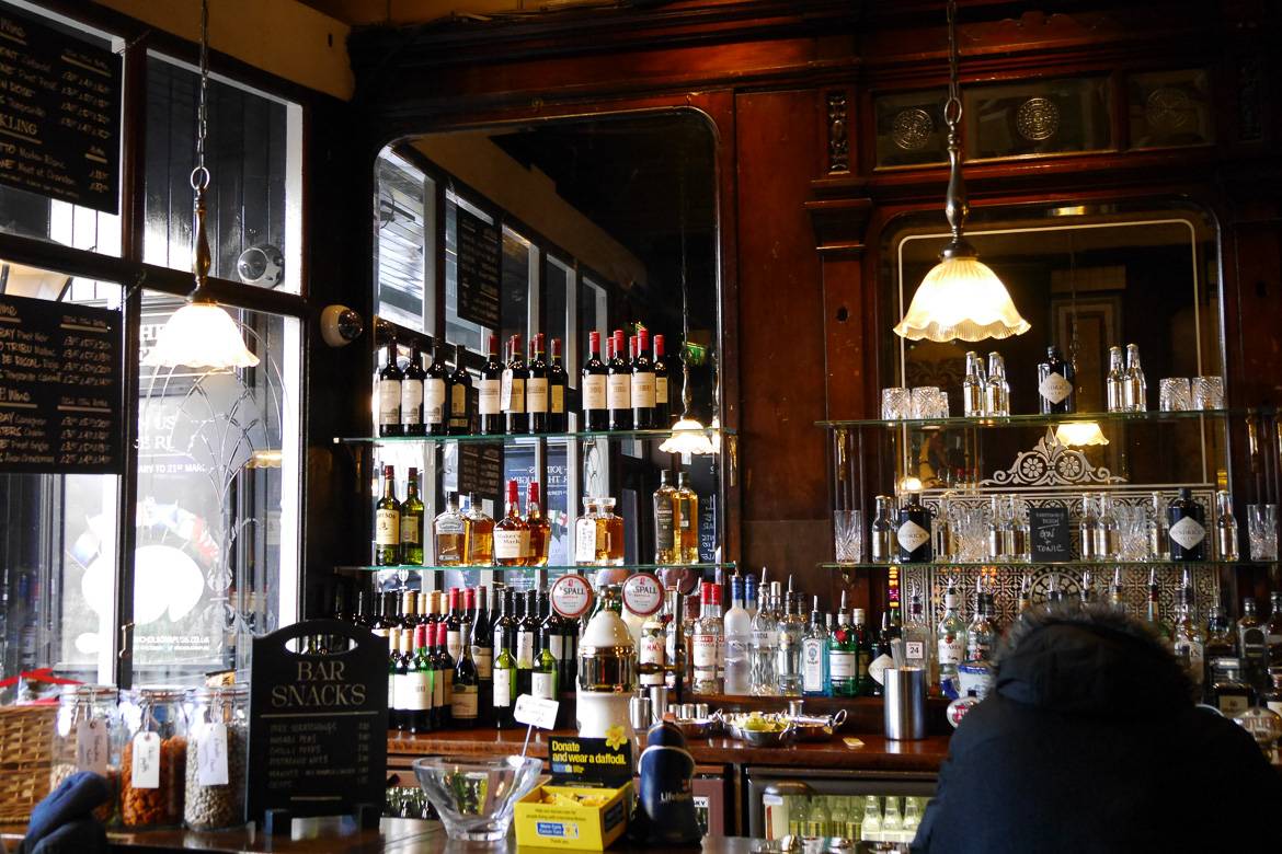 Photo d’un comptoir en bois surmonté d’alcool dans un pub anglais.