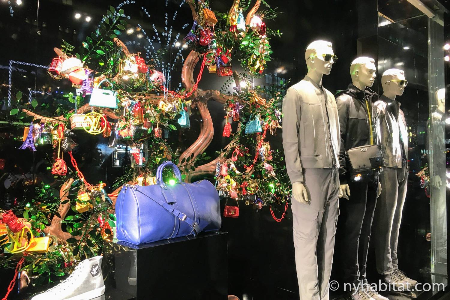 Photo de la vitrine 2018 de Louis Vuitton avec des sapins décorés et des mannequins.