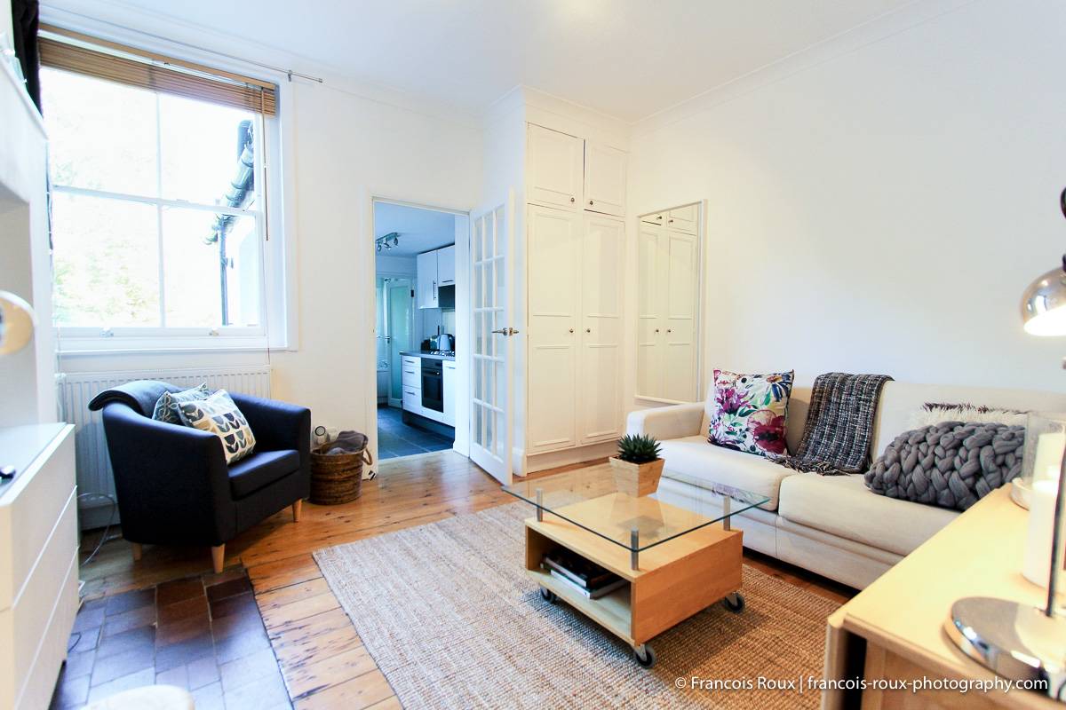 Photo du salon de l’appartement LN-24 avec un canapé-lit, une table basse et une cuisine en alcôve.
