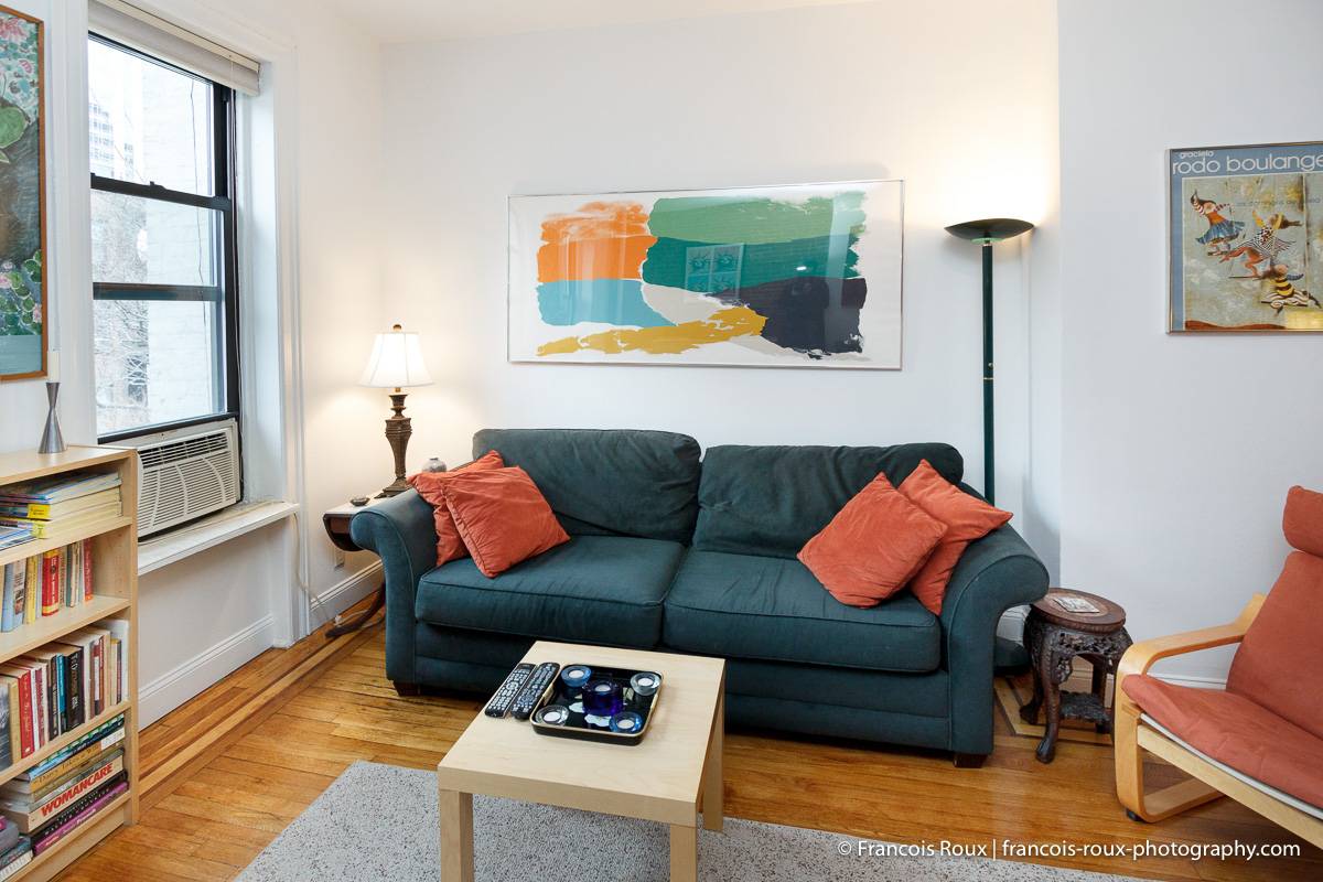 Photo du salon de l’appartement NY-16166 avec un canapé et des peintures murales.