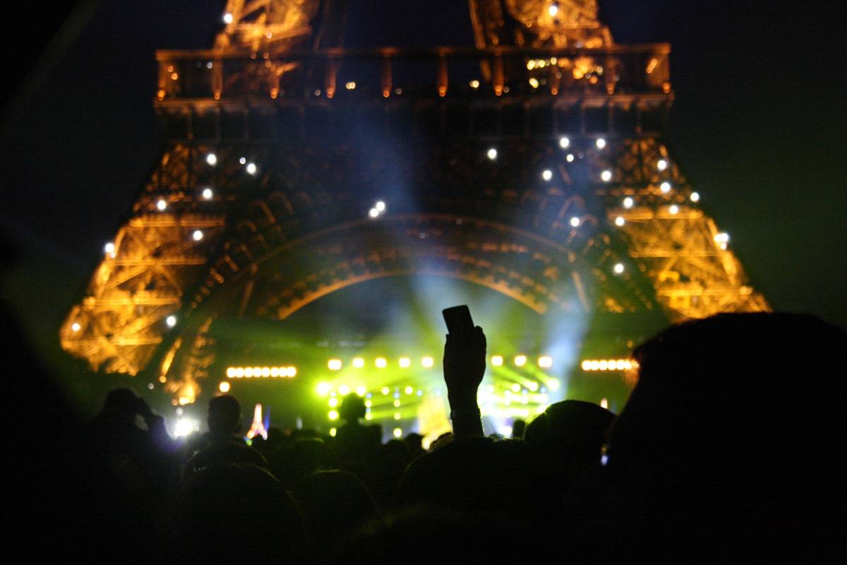 Photo de la foule devant la tour Eiffel, éclairée une fois la nuit tombée.