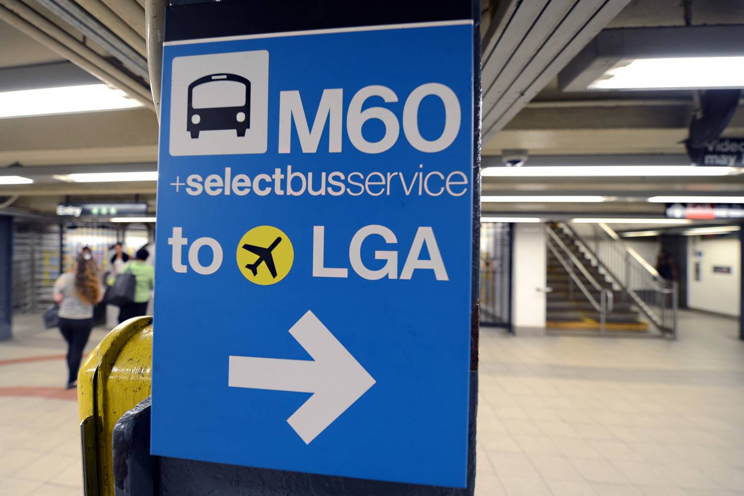 Photo du panneau bleu de la ligne de bus M60 à destination de l’aéroport LaGuardia.
