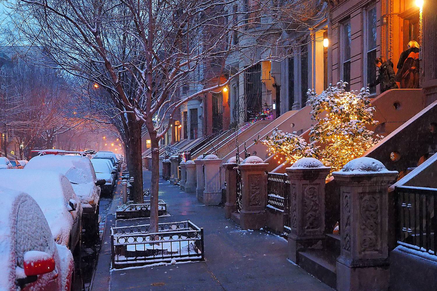Photo d’une rue new-yorkaise bordée de brownstones après une chute de neige.