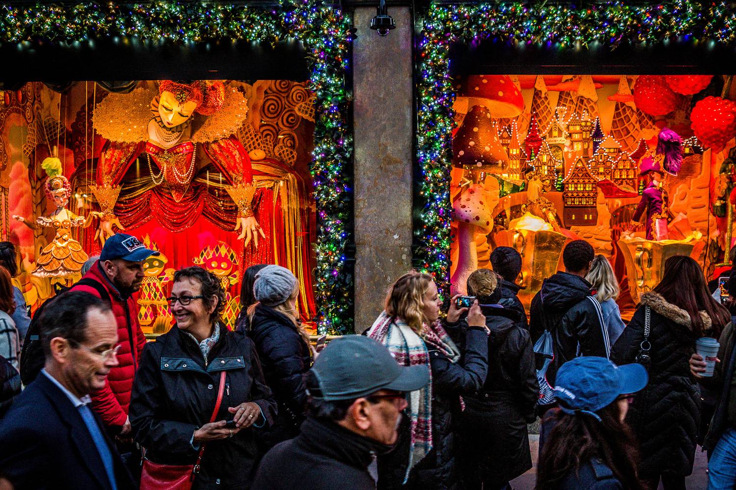 Photo de gens sur le trottoir admirant la devanture du grand magasin Saks Fifth Avenue décoré pour Noël