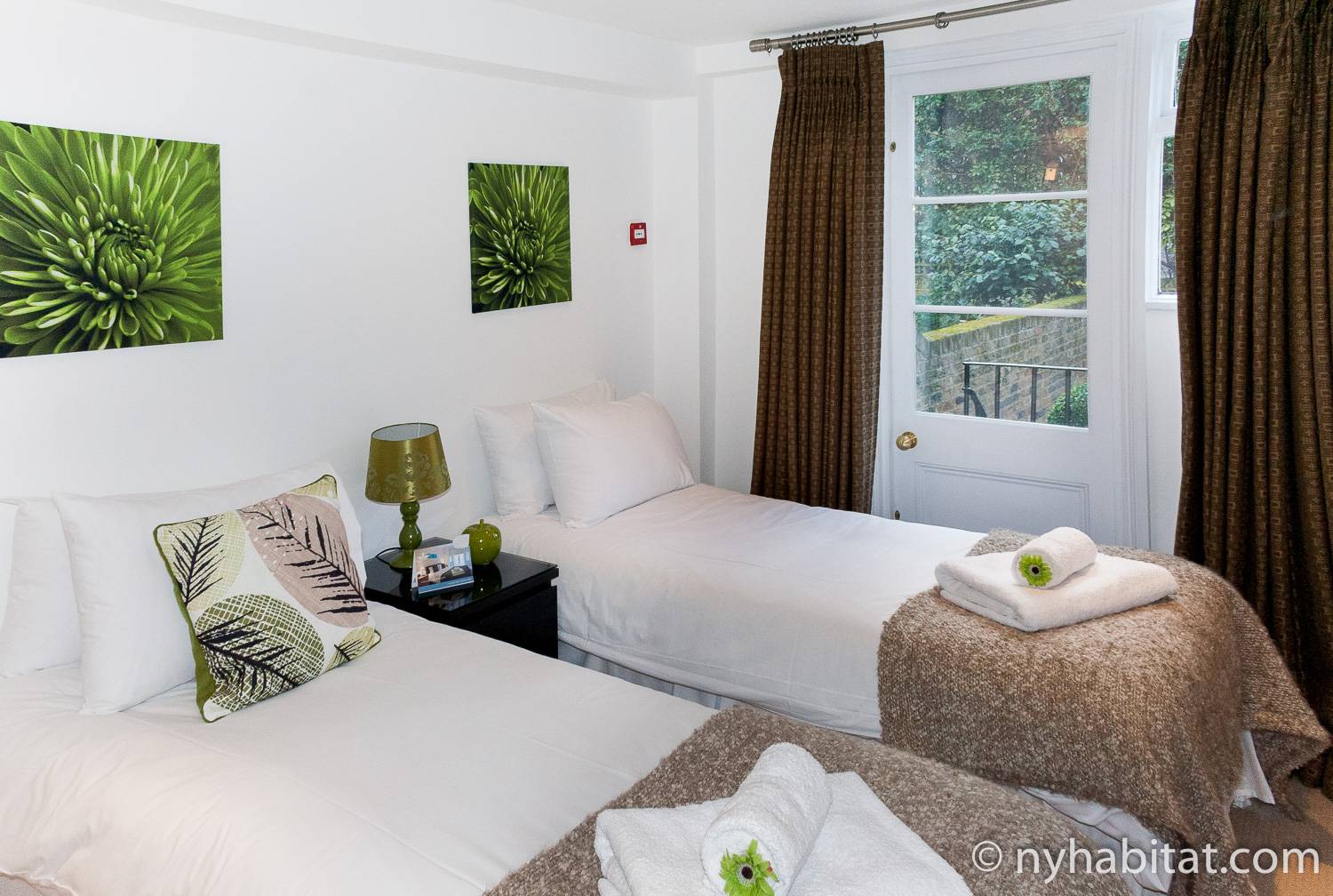Photo de la chambre de l’appartement LN-540 avec deux lits simples et une porte menant vers le jardin.