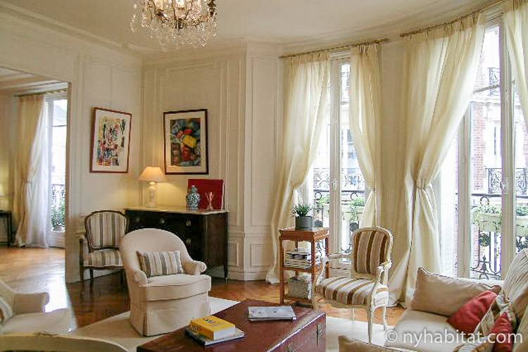Photo de la pièce à vivre de l’appartement PA-3703 avec portes-fenêtres, canapé, et fauteuils.