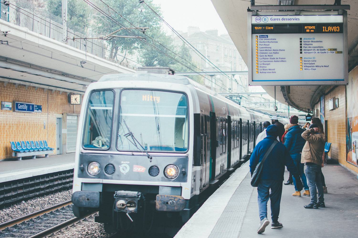 Photographie d’un RER de la ligne B arrivant à une gare dans la banlieue de Paris.