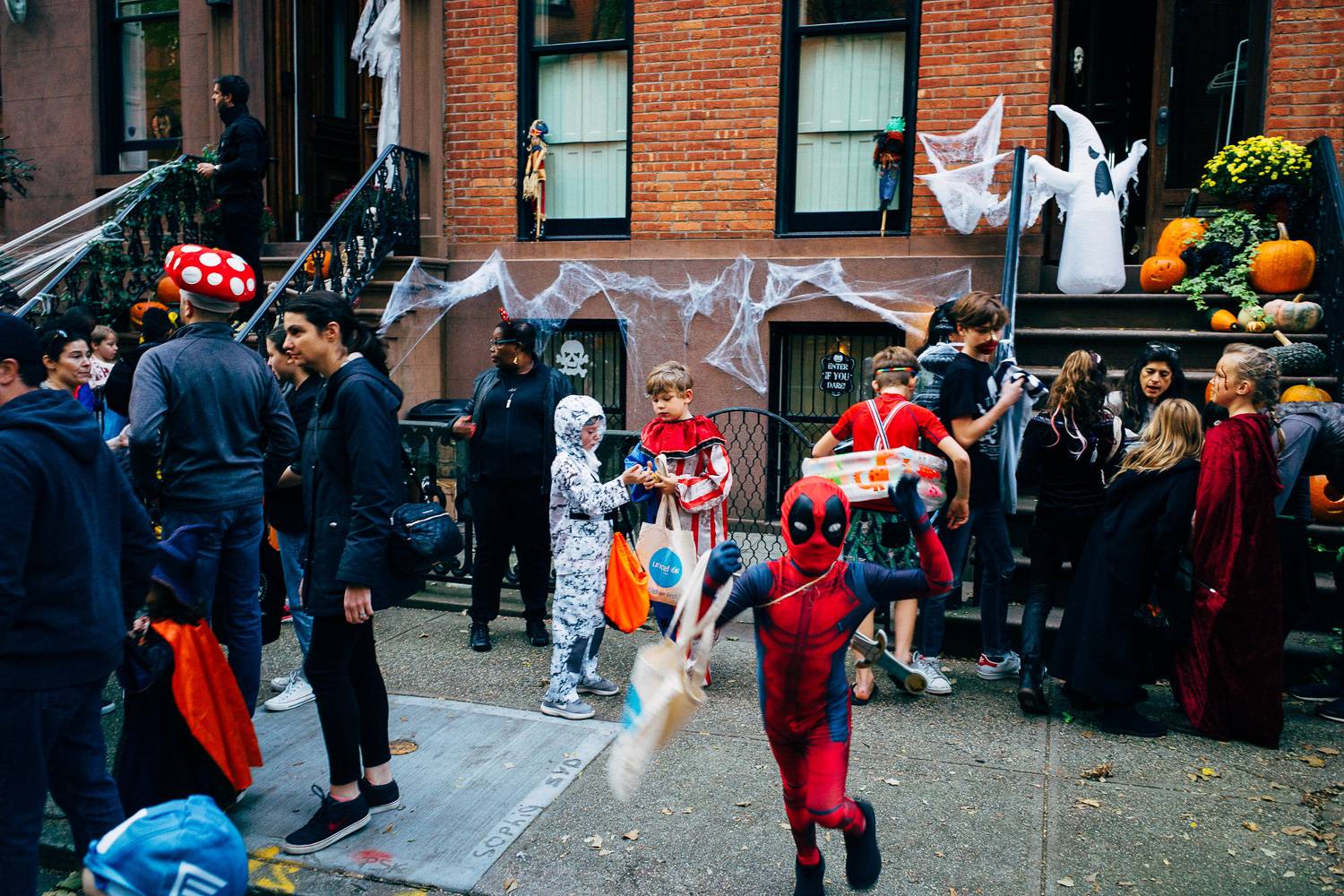 Photo d’enfants déguisés lors d’une chasse aux bonbons sur un trottoir bordant des maisons de ville new-yorkaises.