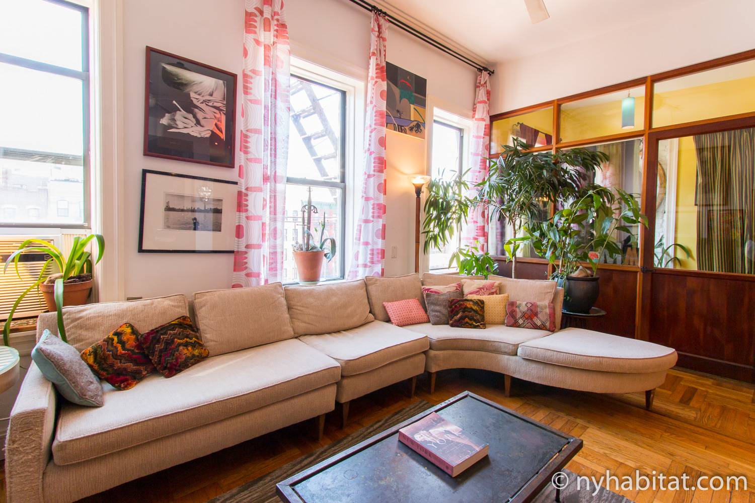 Photo du salon d’un appartement de Lower East Side à Manhattan, avec canapé d’angle et couleurs chaudes.