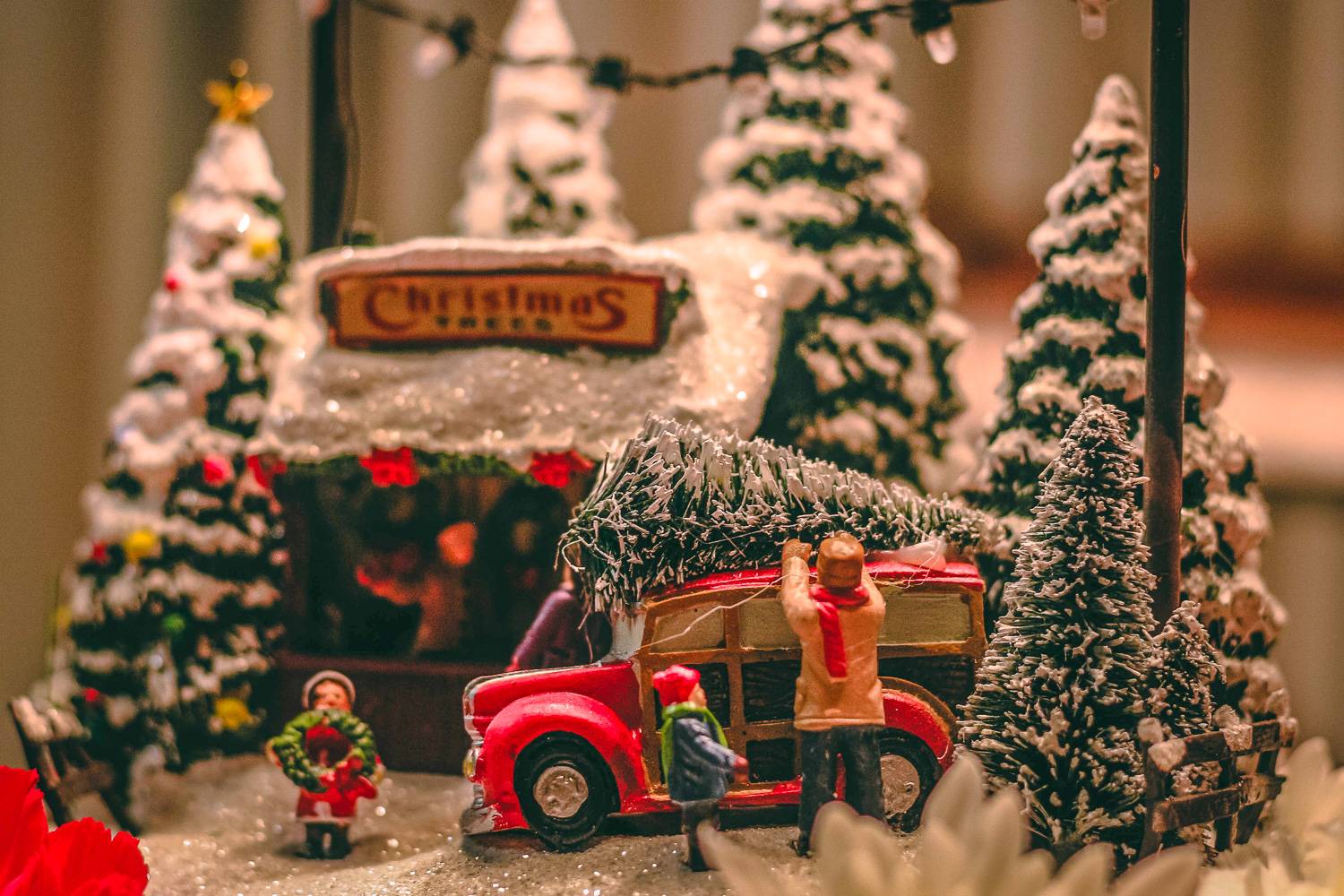 Photo d’une miniature d’une famille à un stand de sapins de Noël, attachant un sapin sur le toit de leur voiture.