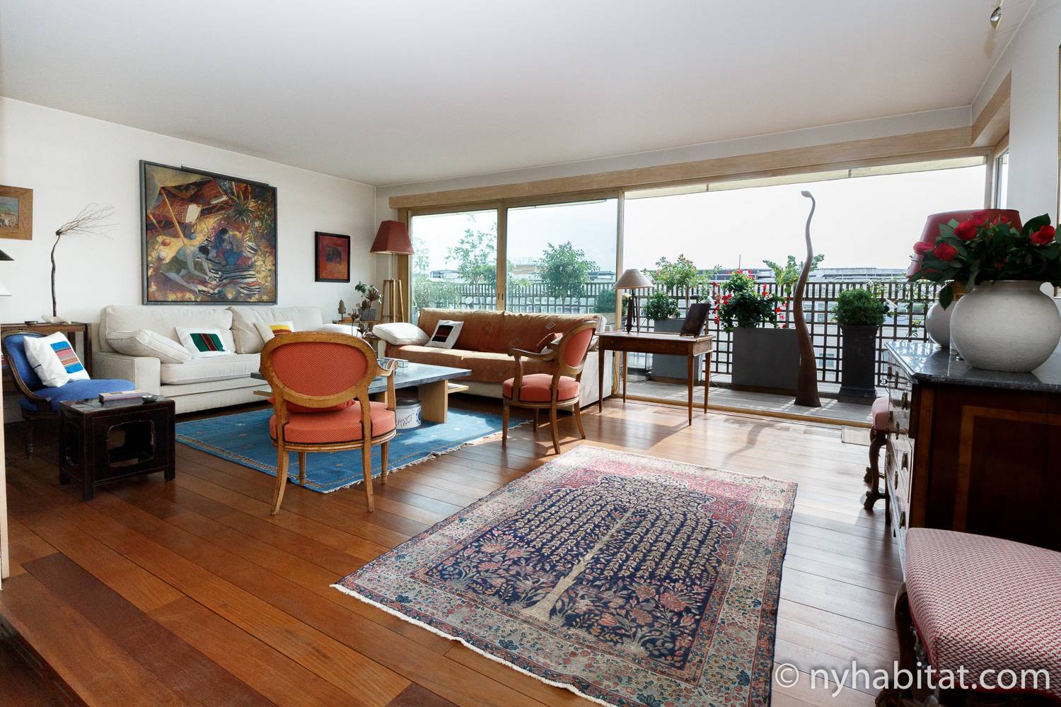 Photo du salon de la location meublée T2 PA-4706 avec un canapé orange, des chaises et un balcon sur la droite.