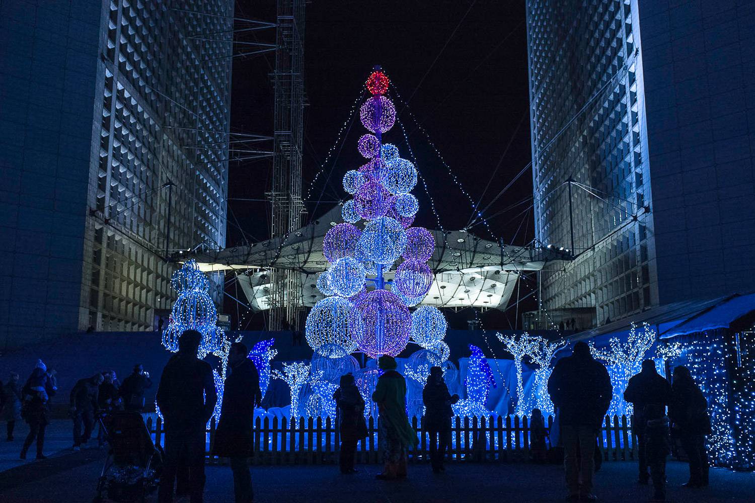 Photo d’un grand sapin de Noël en pleine installation à la Grande Arche, Paris