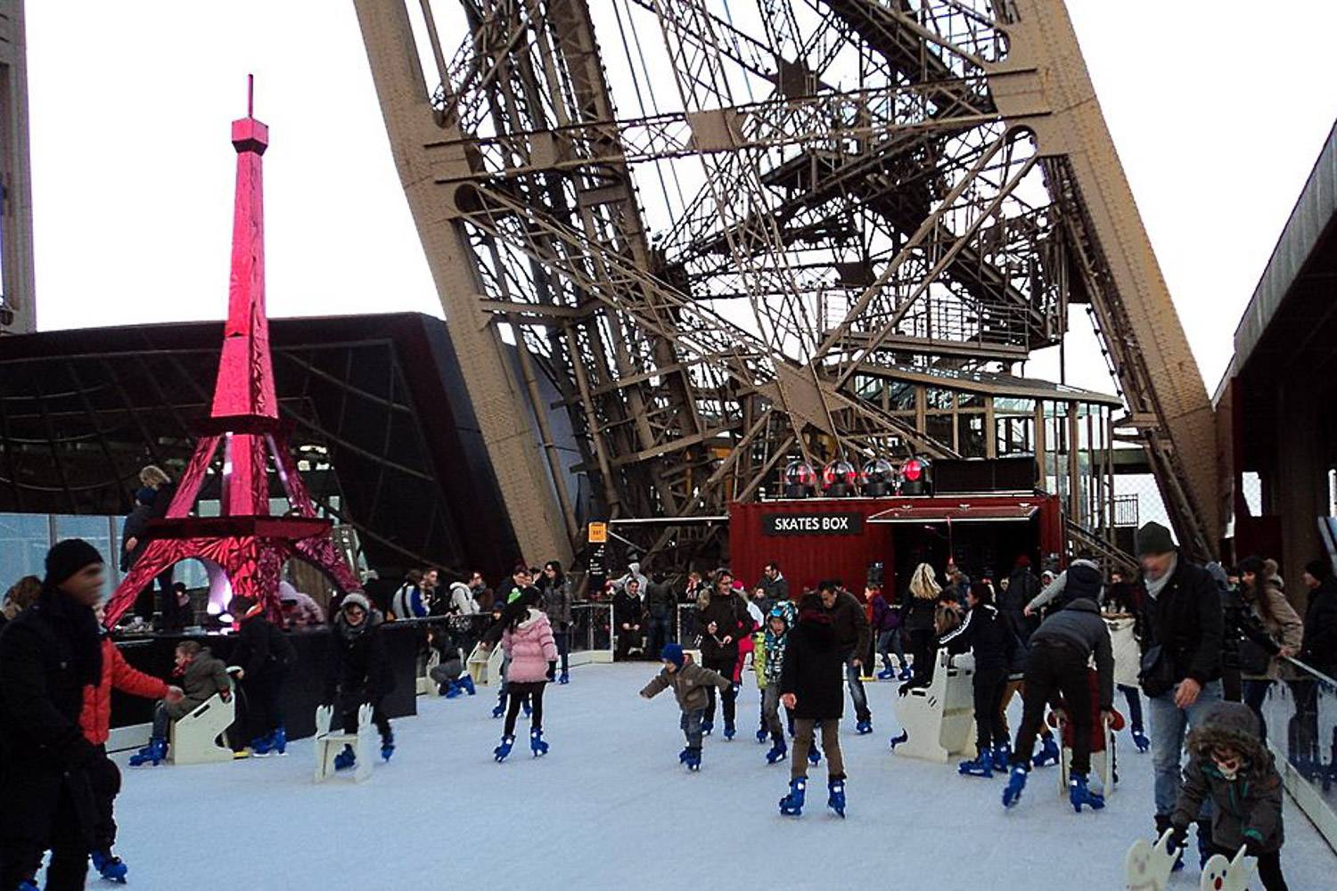 Photo de personnes patinant au pied de la tour Eiffel.