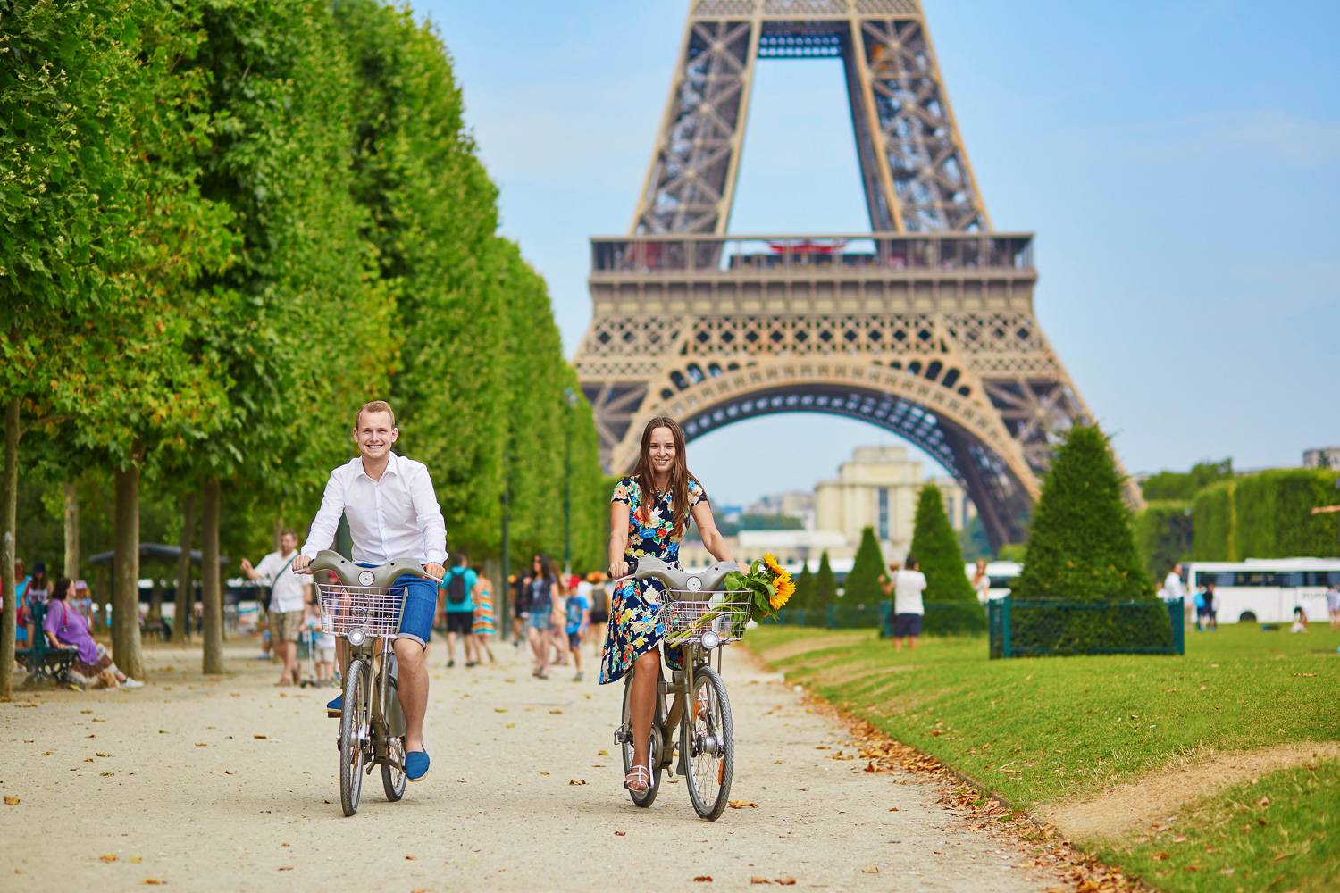 Image d’un couple à vélo dans un parc avec la Tour Eiffel en arrière-plan