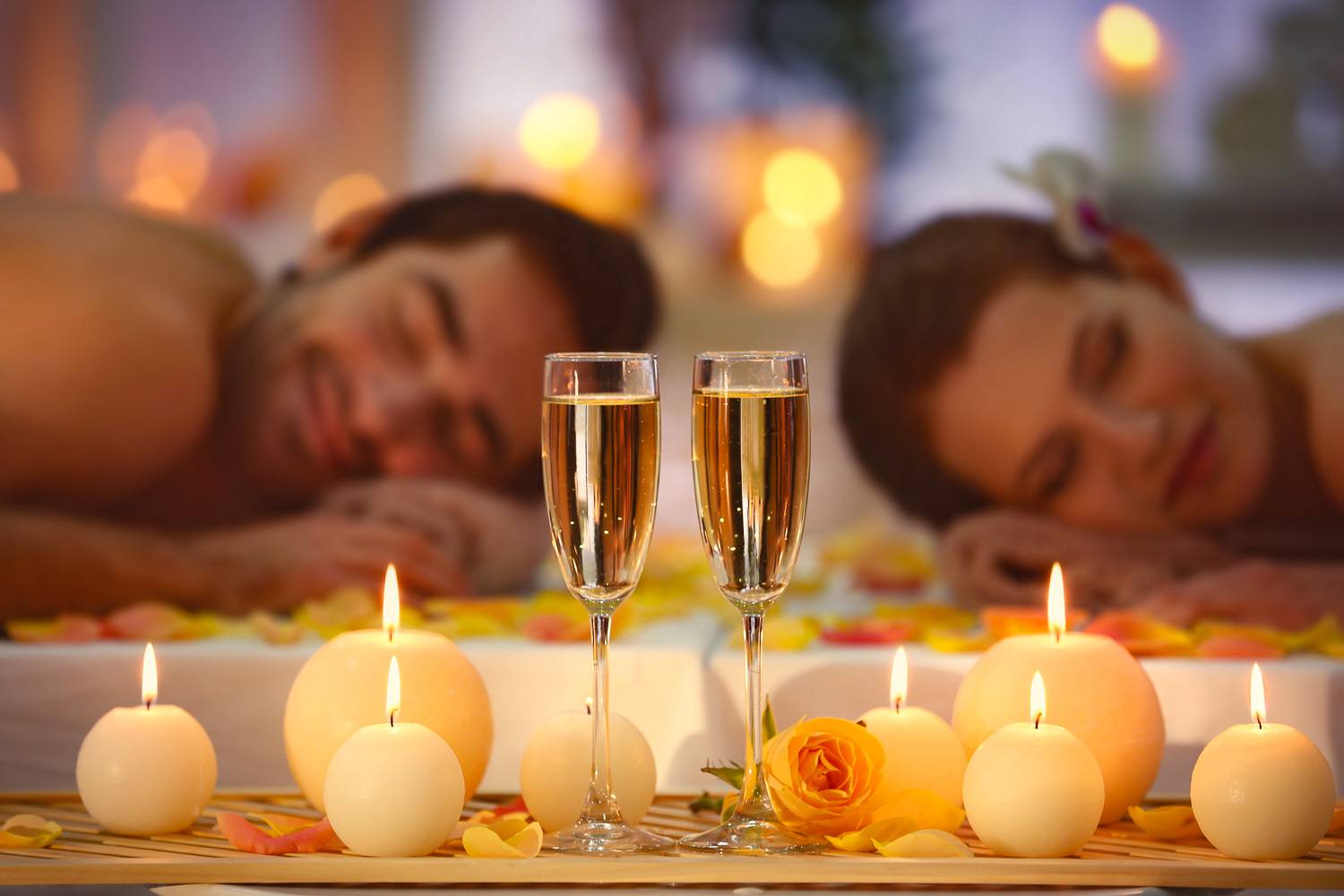 Image d’un couple profitant d’un massage avec du champagne et des bougies au premier plan