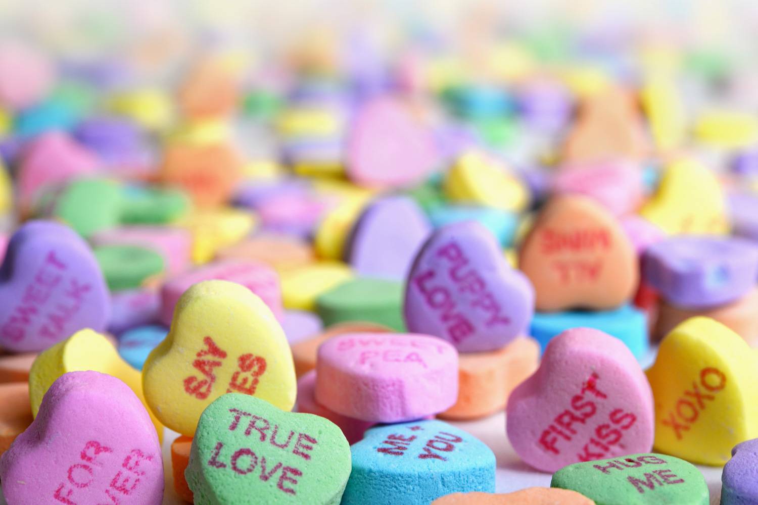 Image de bonbons colorés de la marque Sweethearts pour la Saint-Valentin avec des messages inscrits dessus (Crédit Photo : Unsplash)