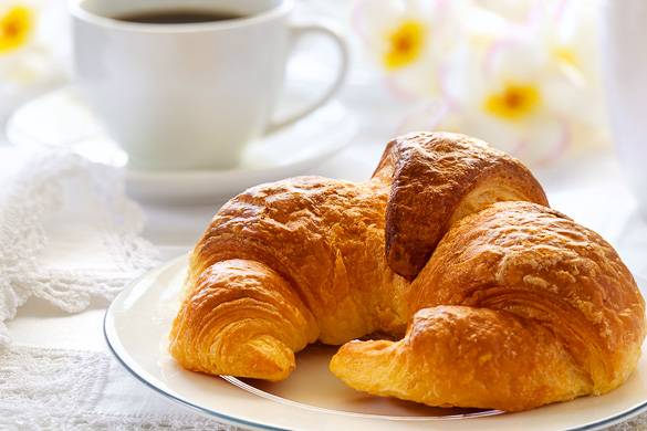 Immagine di un cornetto francese con del caffè
