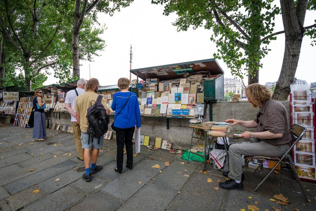 Immagine di un venditore di libri, o bouquiniste, con la sua bancarella accanto alla Senna