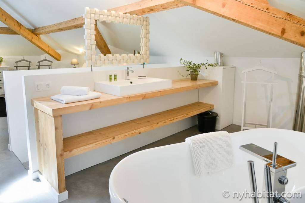 Immagine di un bagno con una vasca Bianca e travi in legno