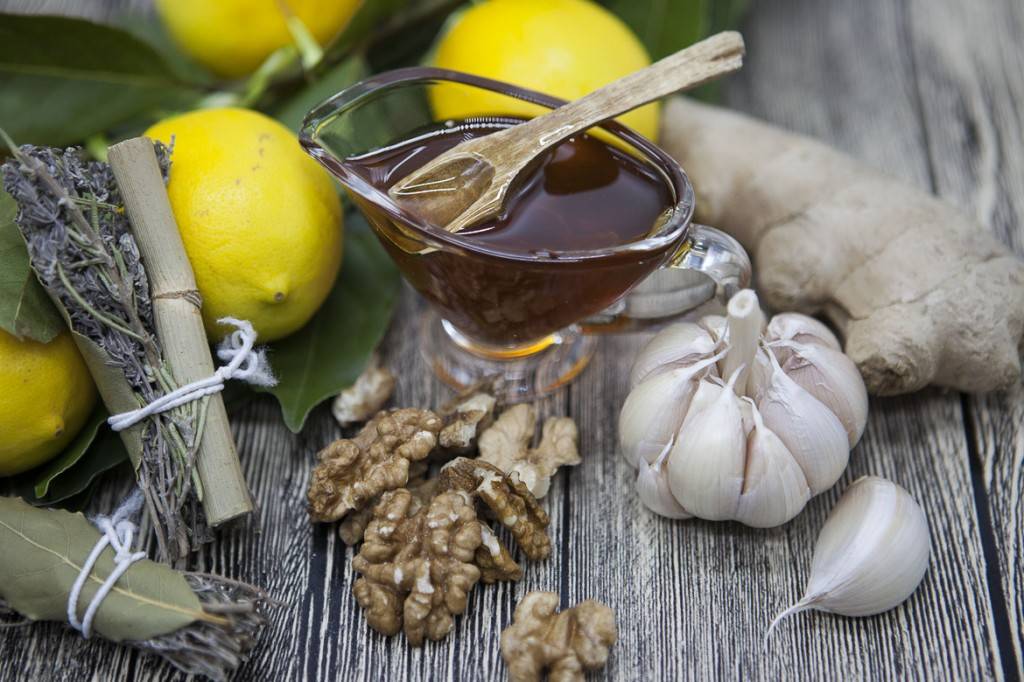 Immagine delle erbe della Provenza, limoni, miele e aglio su un rustico tavolo di legno