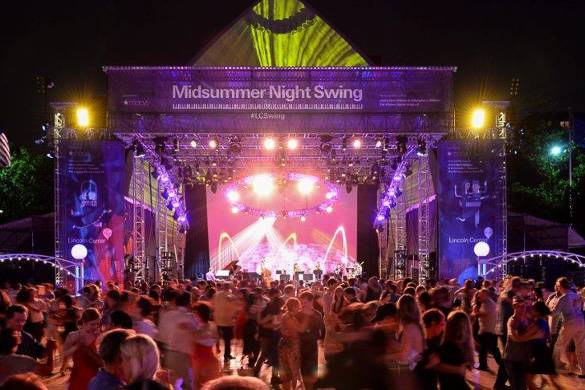 Foto di persone che ballano lo swing di sera con un palco sullo sfondo