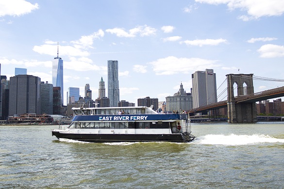 Immagine dell’East River Ferry vicino al ponte di Brooklyn con il panorama di Manhattan sullo sfondo