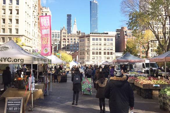 Immagine di persone che passeggiano per i banchi di prodotti agricoli presso l’Union Square Greenmarket