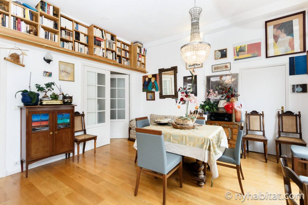 Immagine di uno spazio abitativo in PA-1460 con tavolo e sedie, lampadario e mensola per libri.
