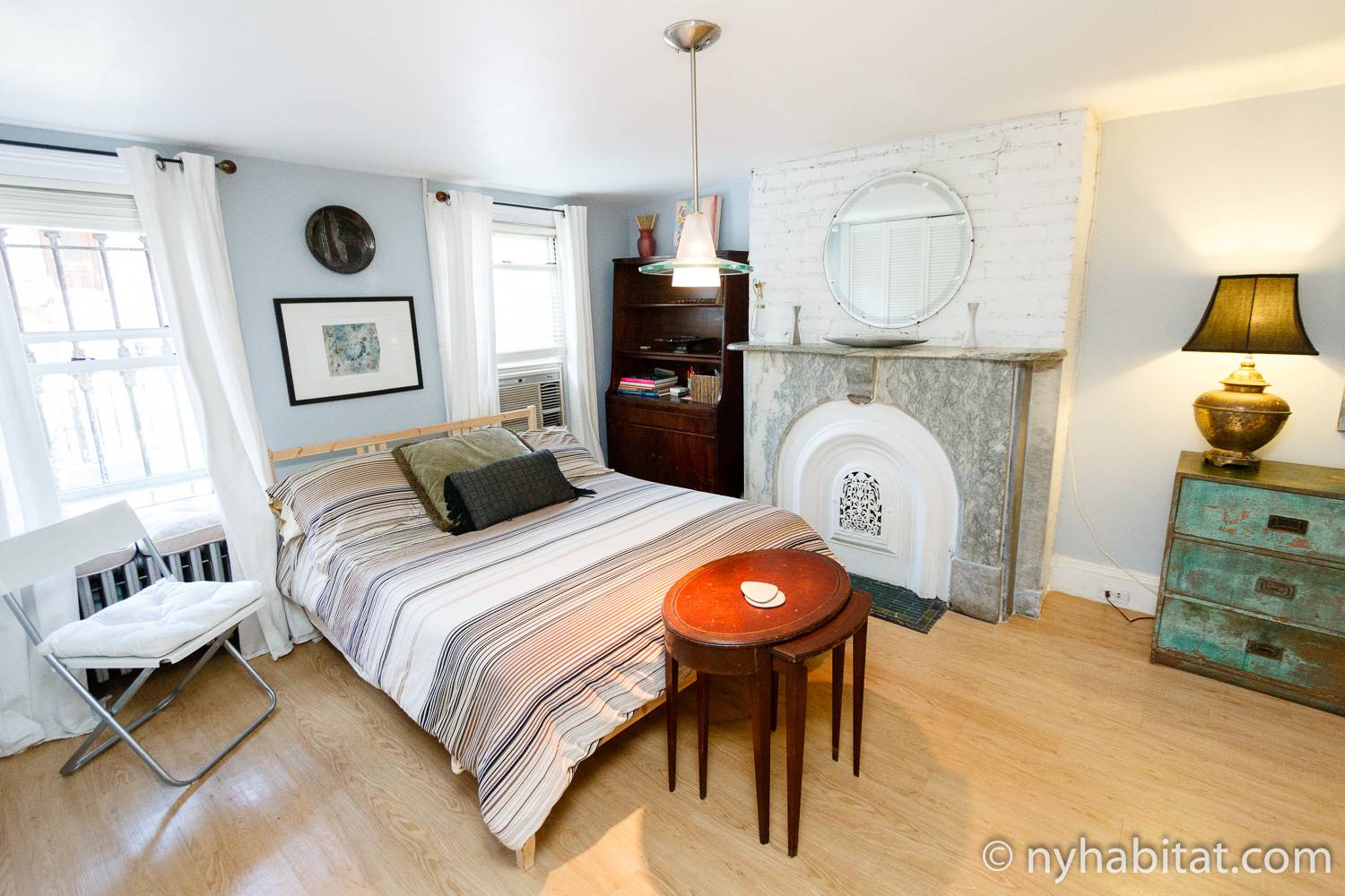 Immagine dello spazio abitativo di NY-16024 con un grande letto, ripiano per libri e caminetto ornamentale.